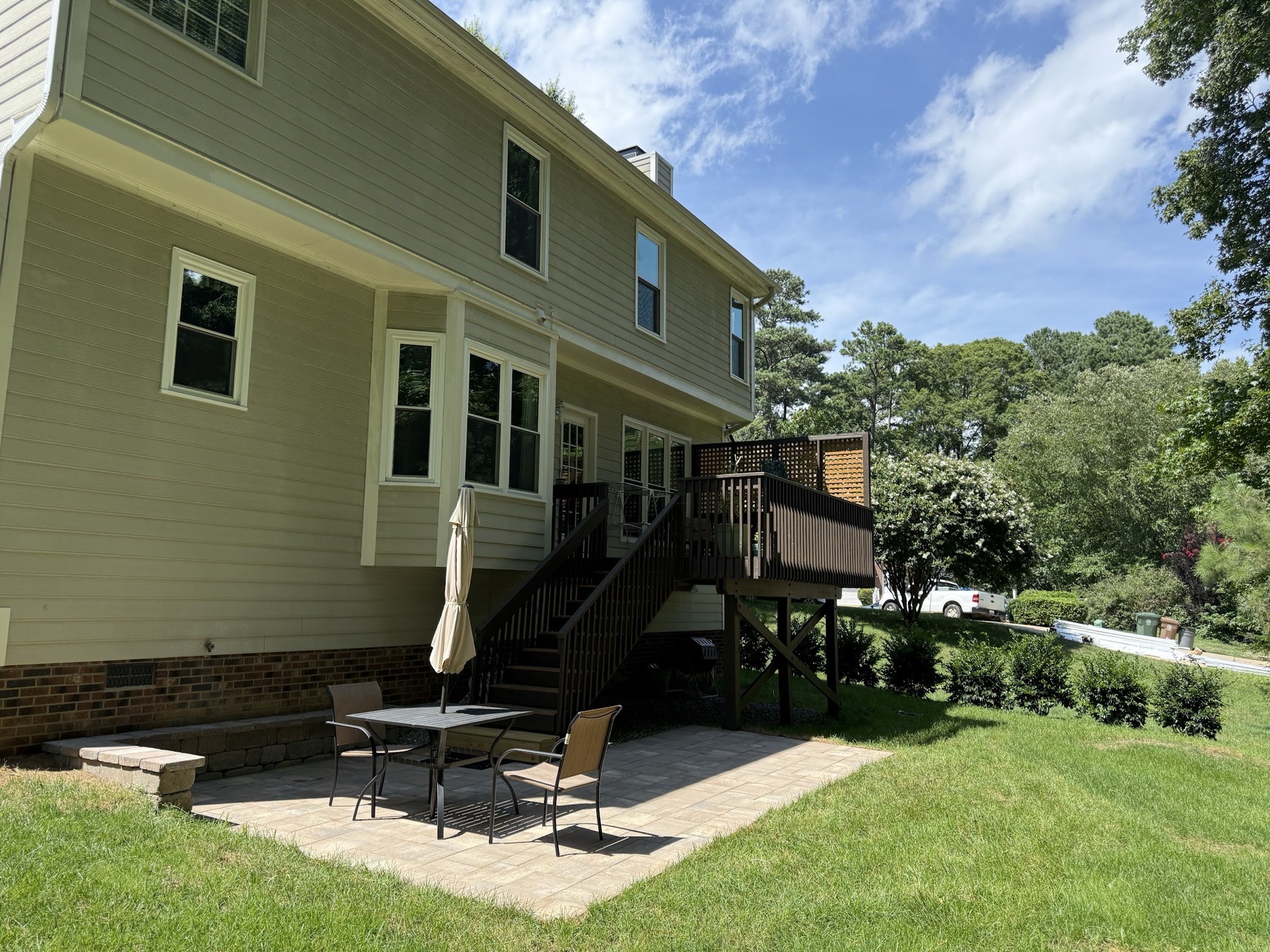 A paver patio tucked beneath a raised deck for a shaded seating area.